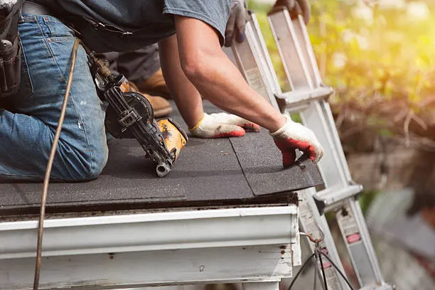 1. A man applies asphalt on a flat roof, using a bucket and roll for maintenance and repair work.